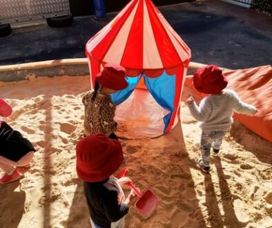 Toddlers in red bucket hats playing in the shaded sandpit at Maroubra Junction Early Education Centre